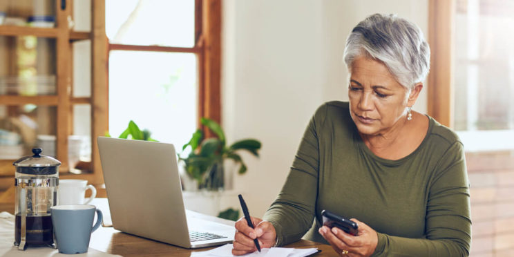 woman planning her retirement finances with pen, paper, and laptop
